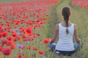 Woman meditating in poppy field